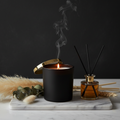 Lonniemac's Luxury Scented Candle in matte black vessel with gold lid on marble tray